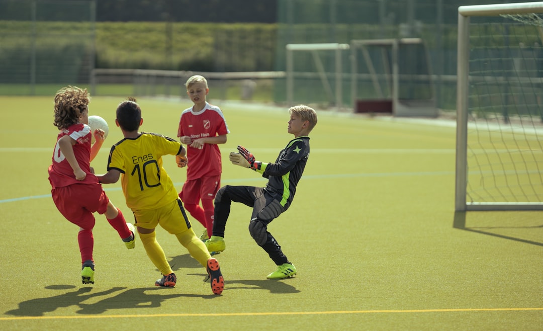 2 boys in black and yellow soccer uniform running on green field during daytime