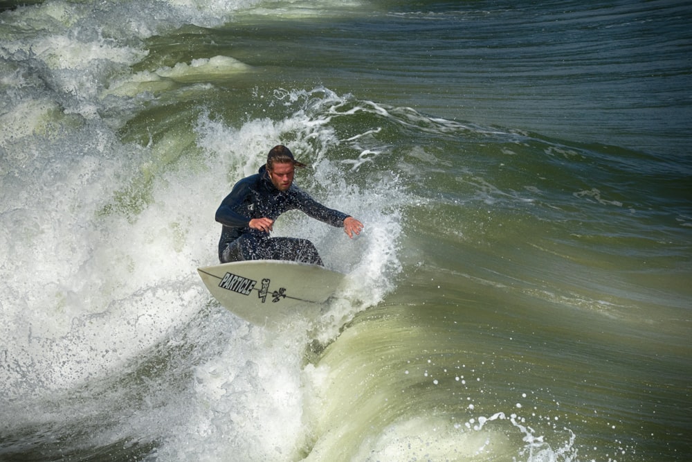 man in black and red jacket surfing on sea waves during daytime