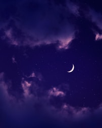 A golden crescent moon surrounded by shimmering stars on a dark purple background.