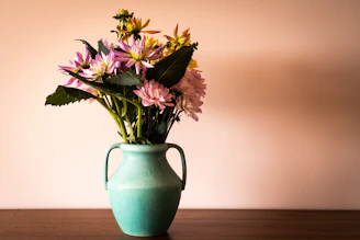 Artistic shot of a floral centerpiece combining turquoise and beige tones on a clean white tablecloth.