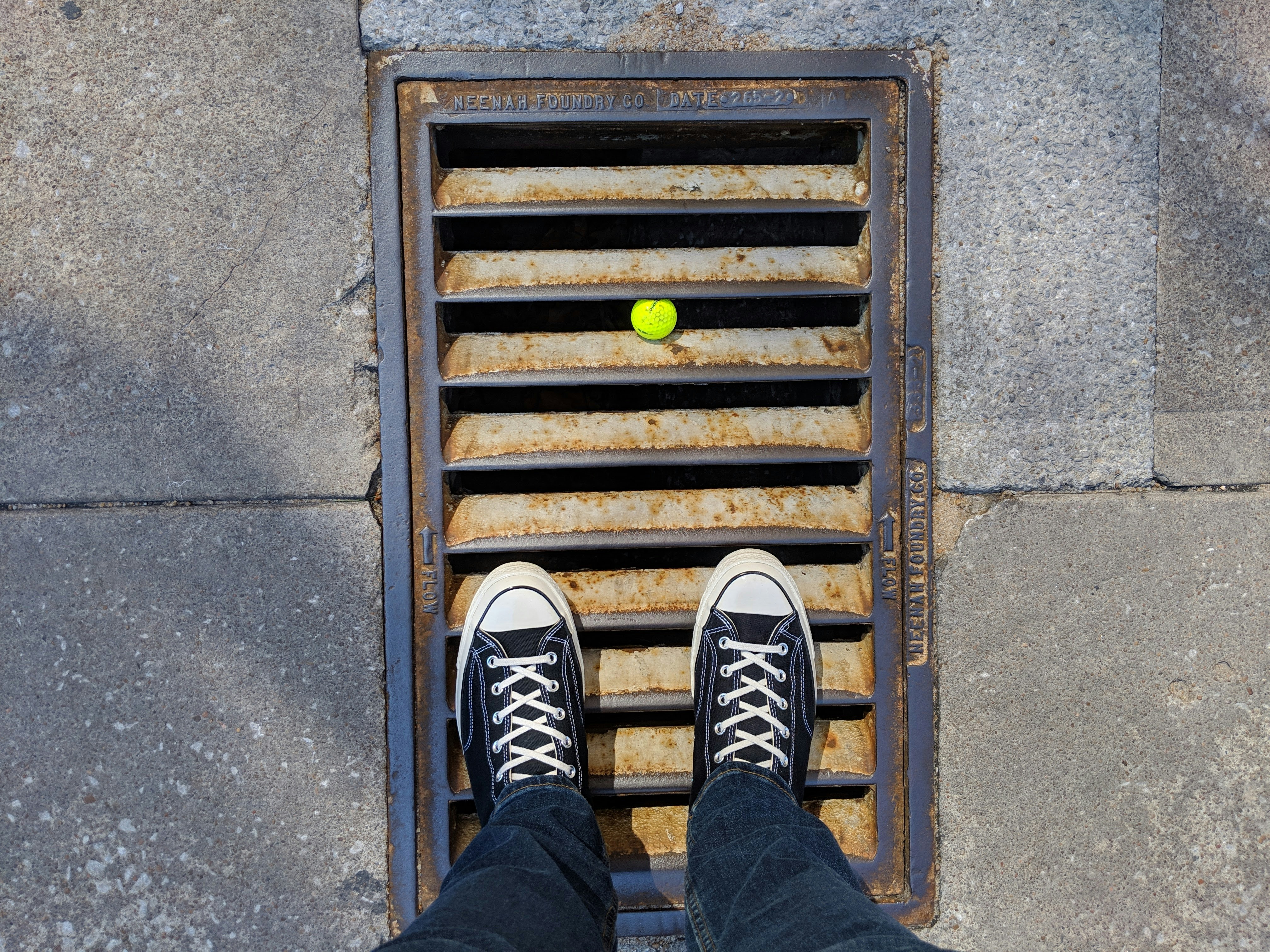 person in blue denim jeans and black and white sneakers standing on brown metal stairs