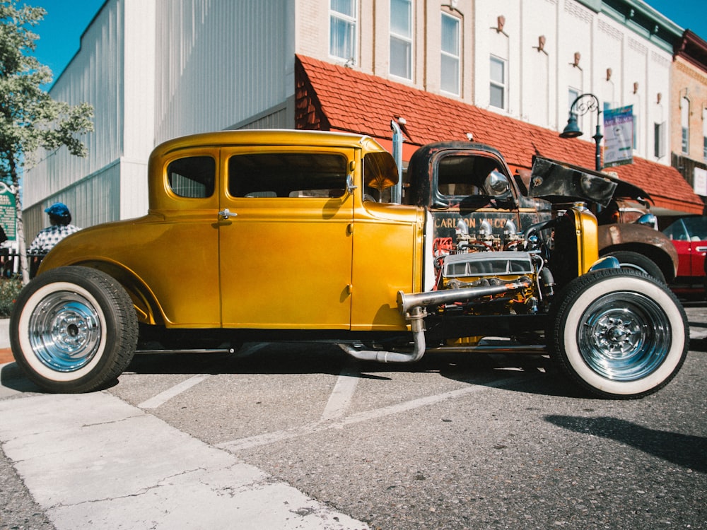 yellow vintage car parked near white building