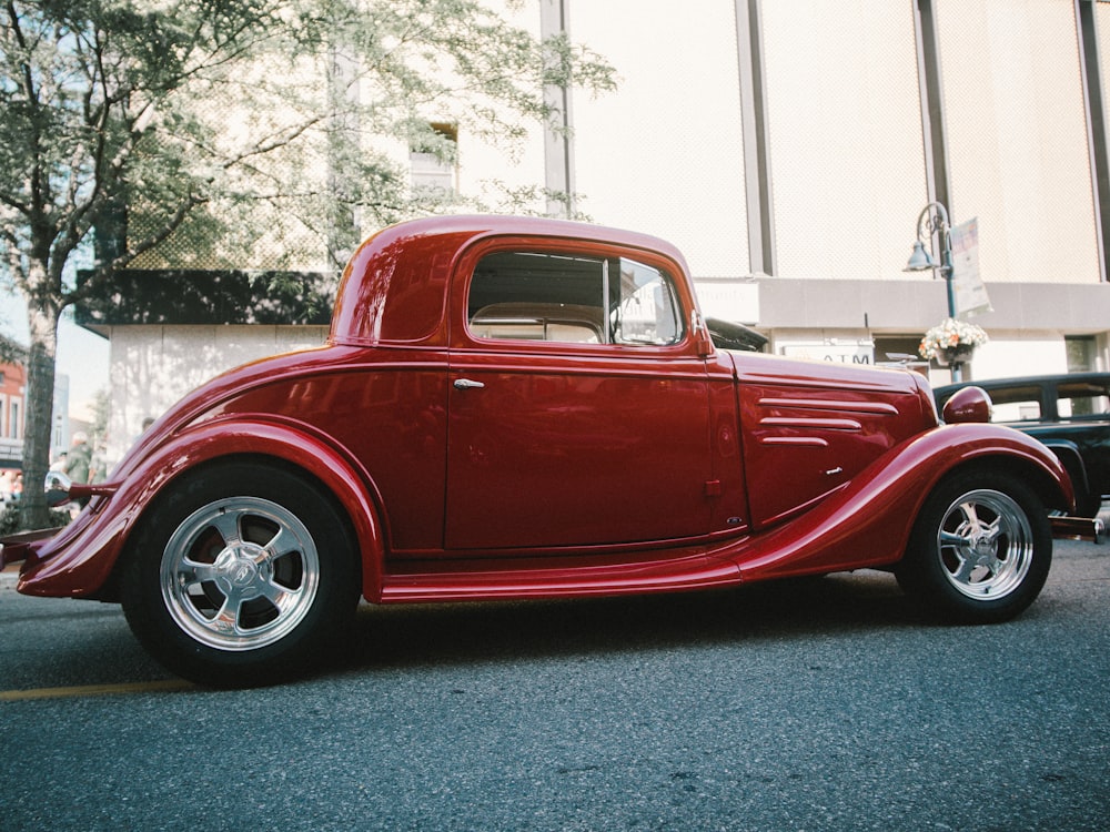 red vintage car on gray asphalt road during daytime