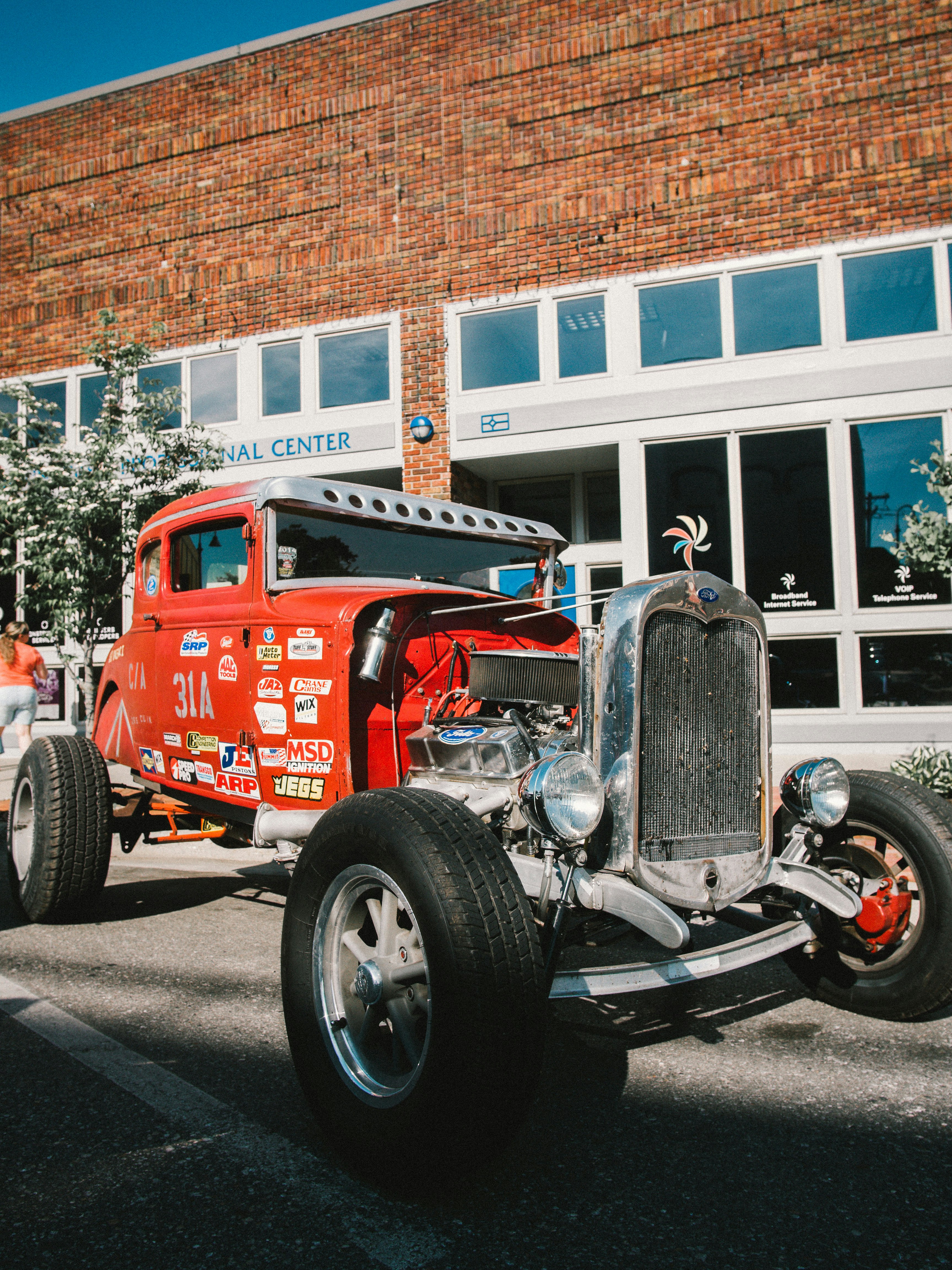 red and black vintage car parked near white and brown building during daytime