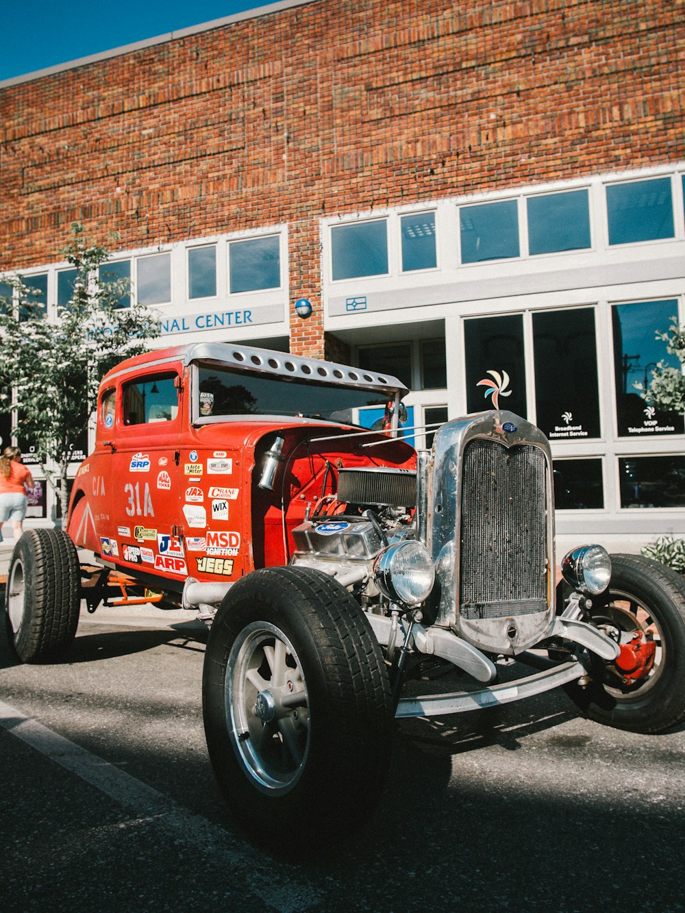 red and black vintage car parked near white and brown building during daytime