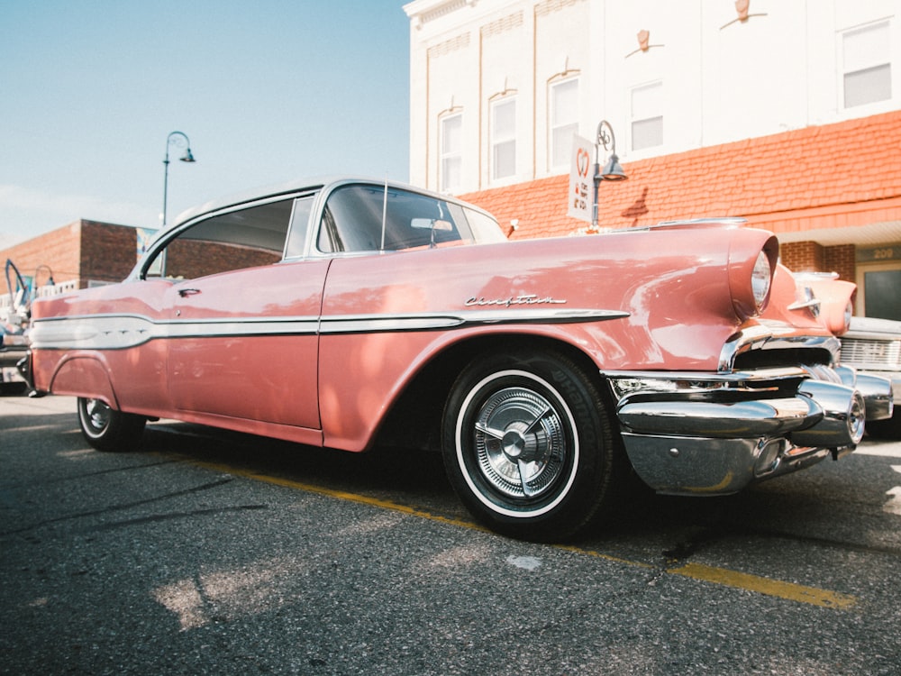 red and black vintage car parked on gray asphalt road during daytime