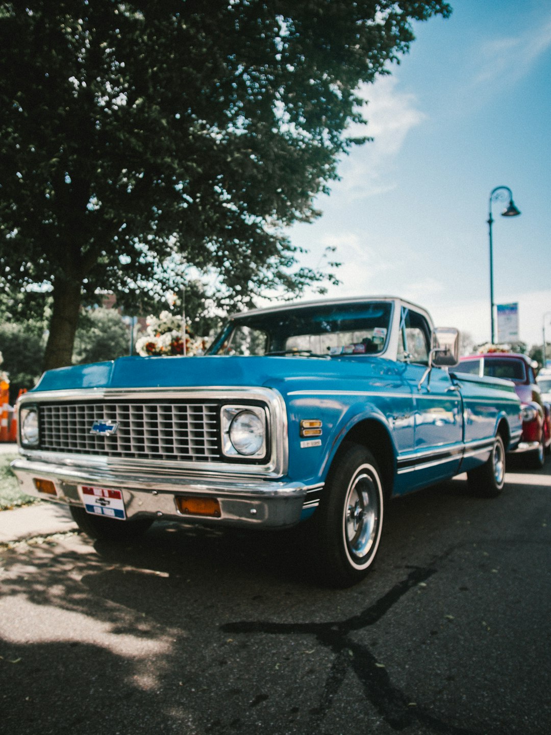 blue chevrolet single cab pickup truck parked on gray concrete road during daytime