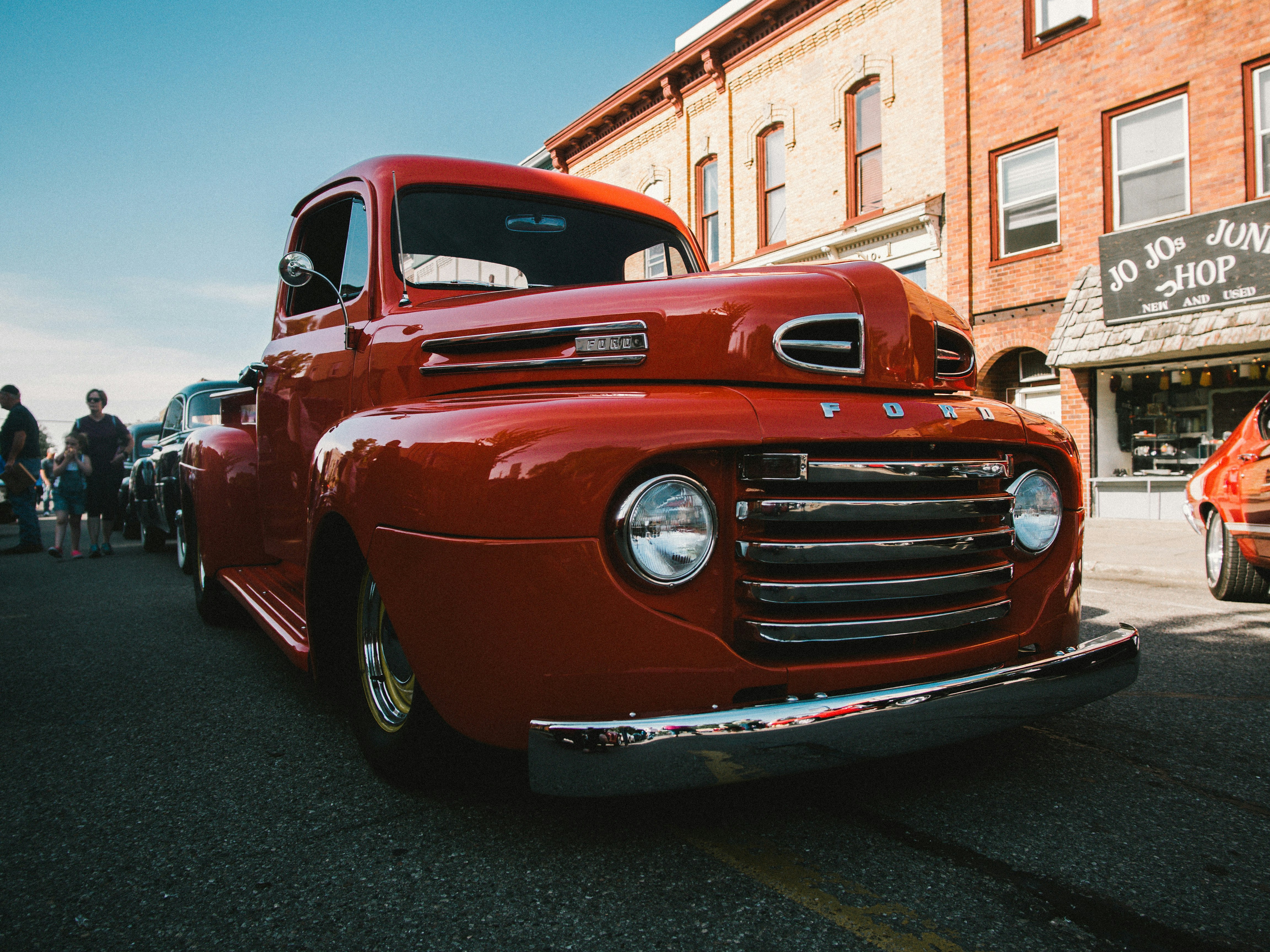 red vintage car parked on gray asphalt road during daytime