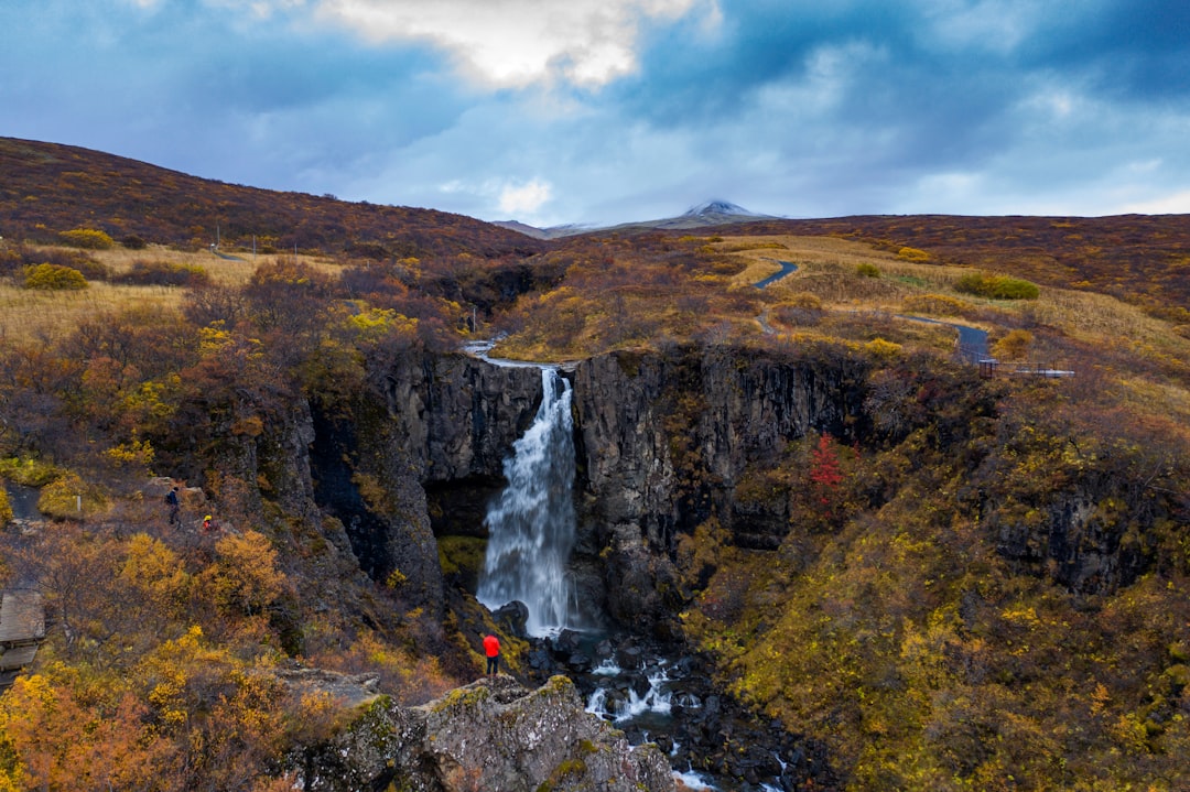 waterfalls on brown rocky mountain under white cloudy sky during daytime