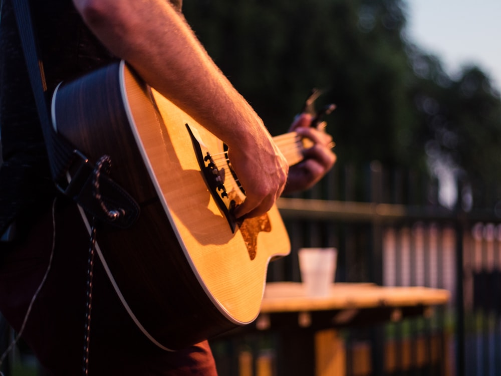 Mann im schwarzen T-Shirt spielt braune akustische Gitarre