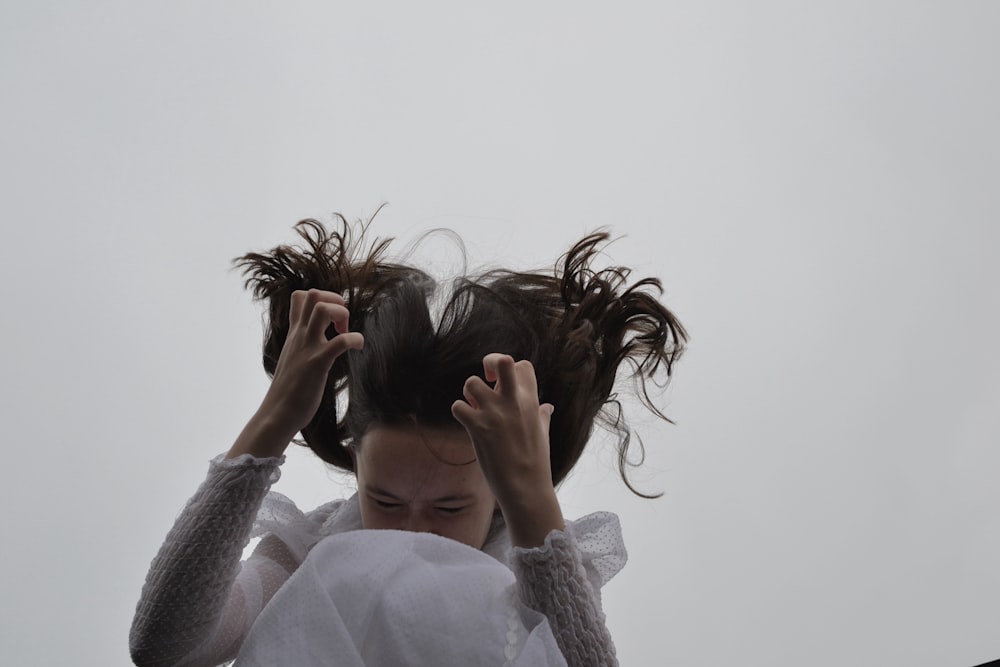 woman in white long sleeve shirt covering her face with her hair