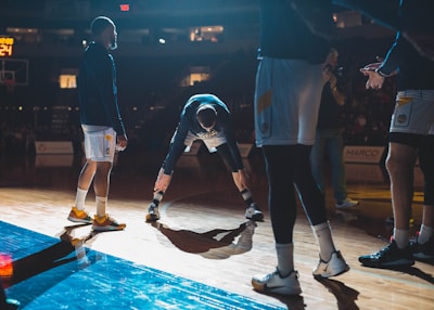 A coach giving hands-on basketball training to focused young players under soft magenta lighting.