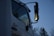 A close-up of a white truck featuring large side mirrors reflecting the evening light, with trees visible in the background. The name 'Joe' is written on the side of the door, and the word 'SERVICE' is partially visible below it.