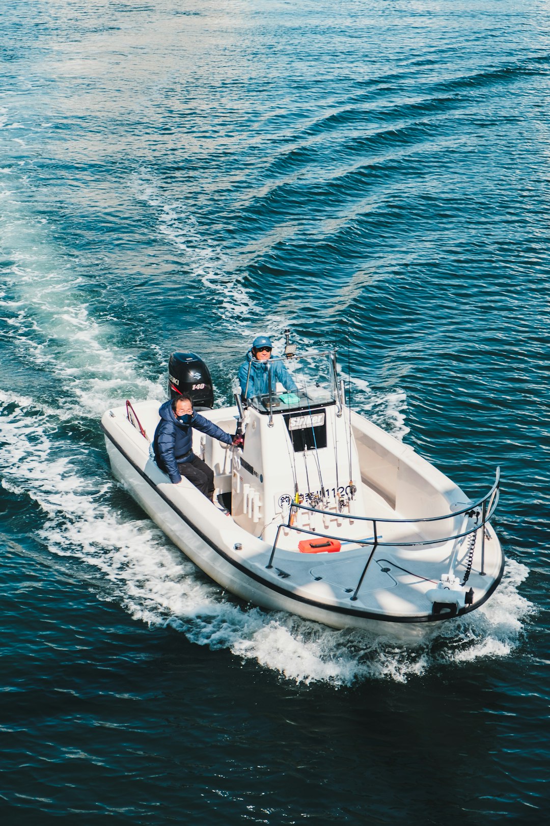 man in white shirt riding white and red boat on blue sea during daytime