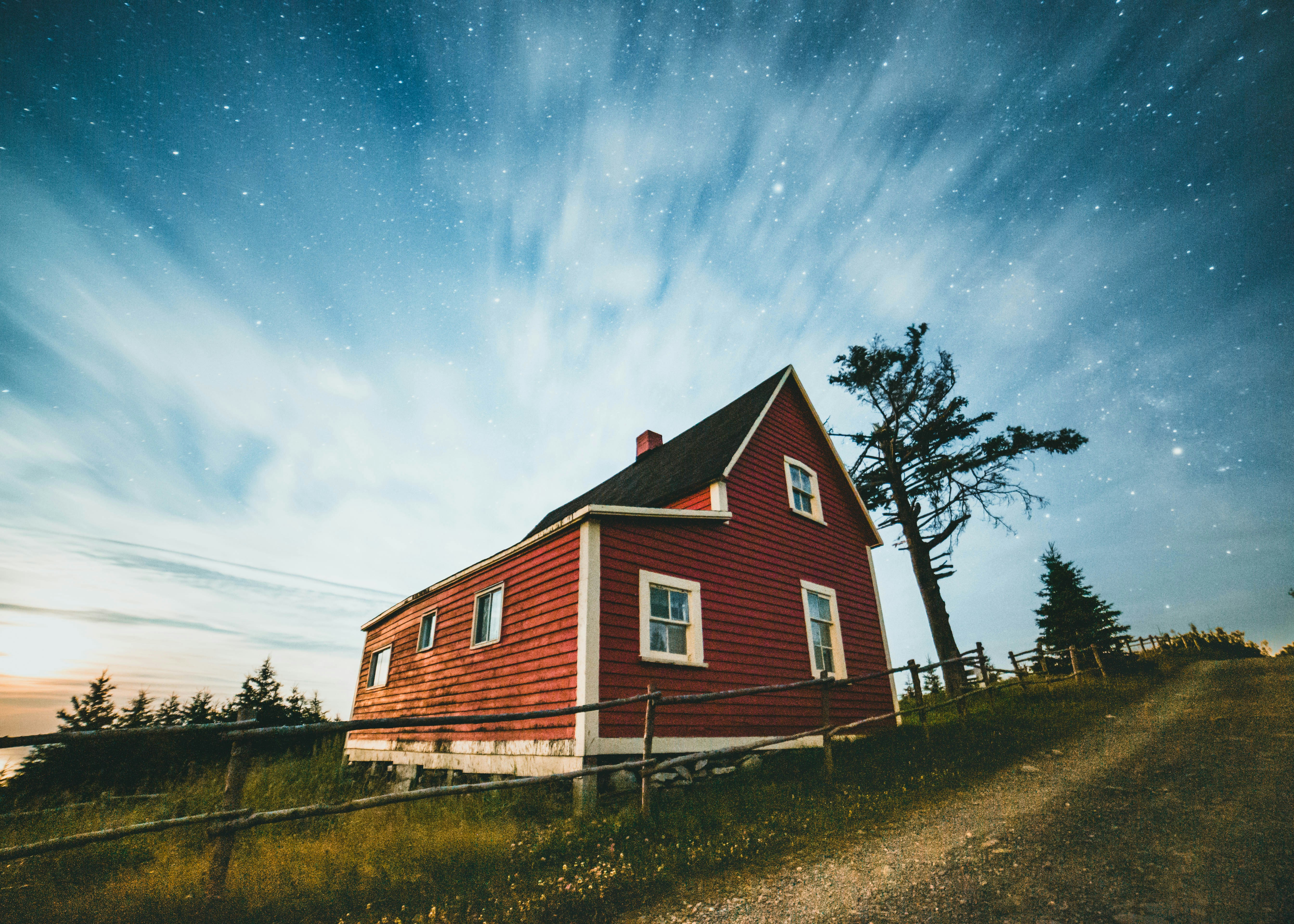 brown and white wooden house near green trees under blue sky during daytime