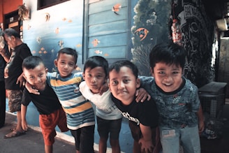 Five young boys stand with their arms around each other.