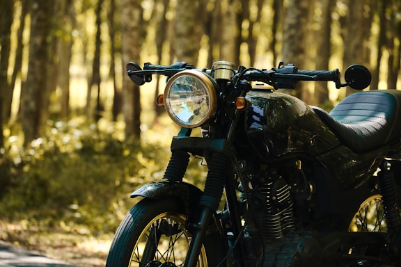 A vintage motorcycle parked beside a rustic garage with warm sunlight filtering through.