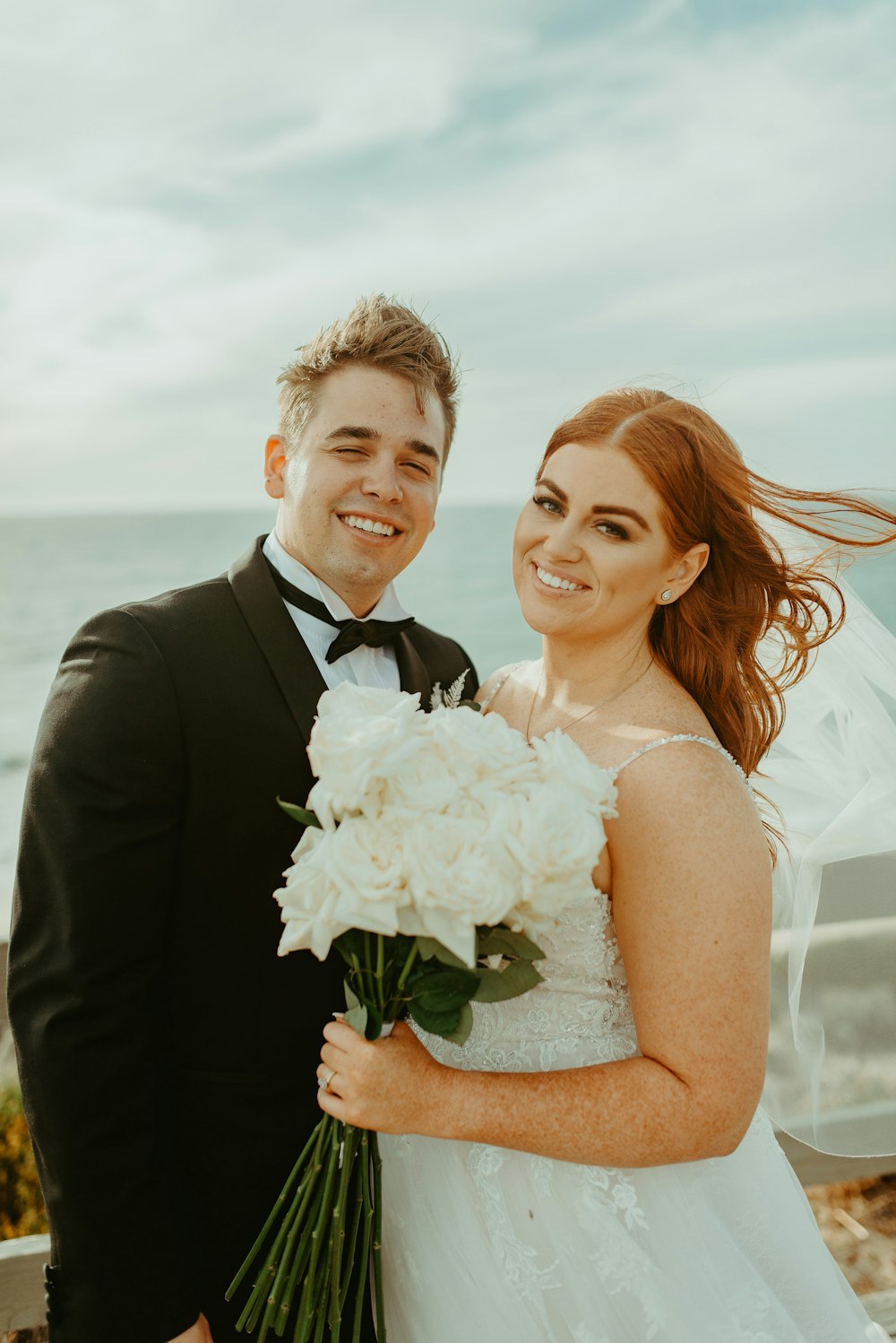 man in black suit jacket hugging woman in white wedding dress