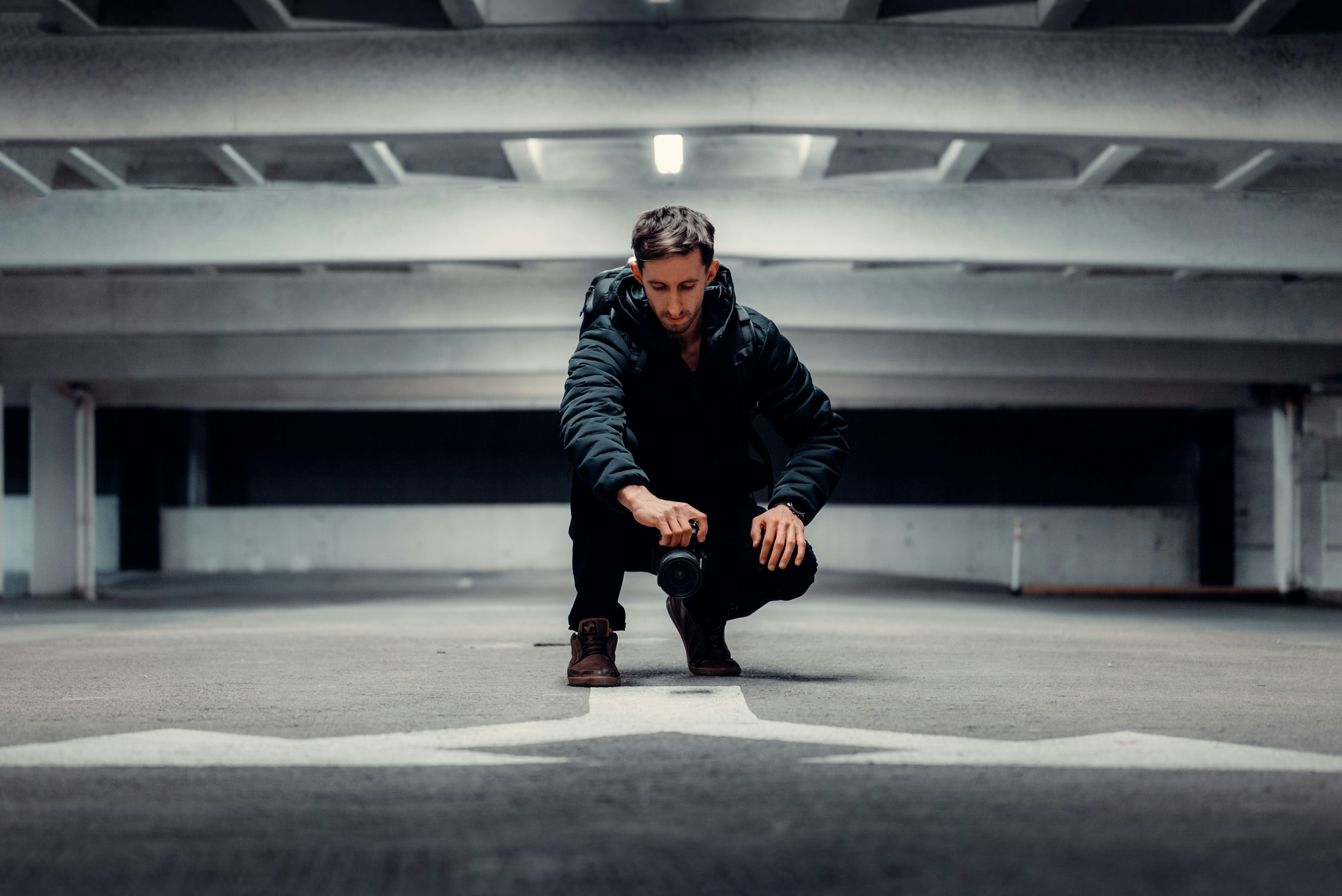 man in black jacket and black pants sitting on gray concrete stairs