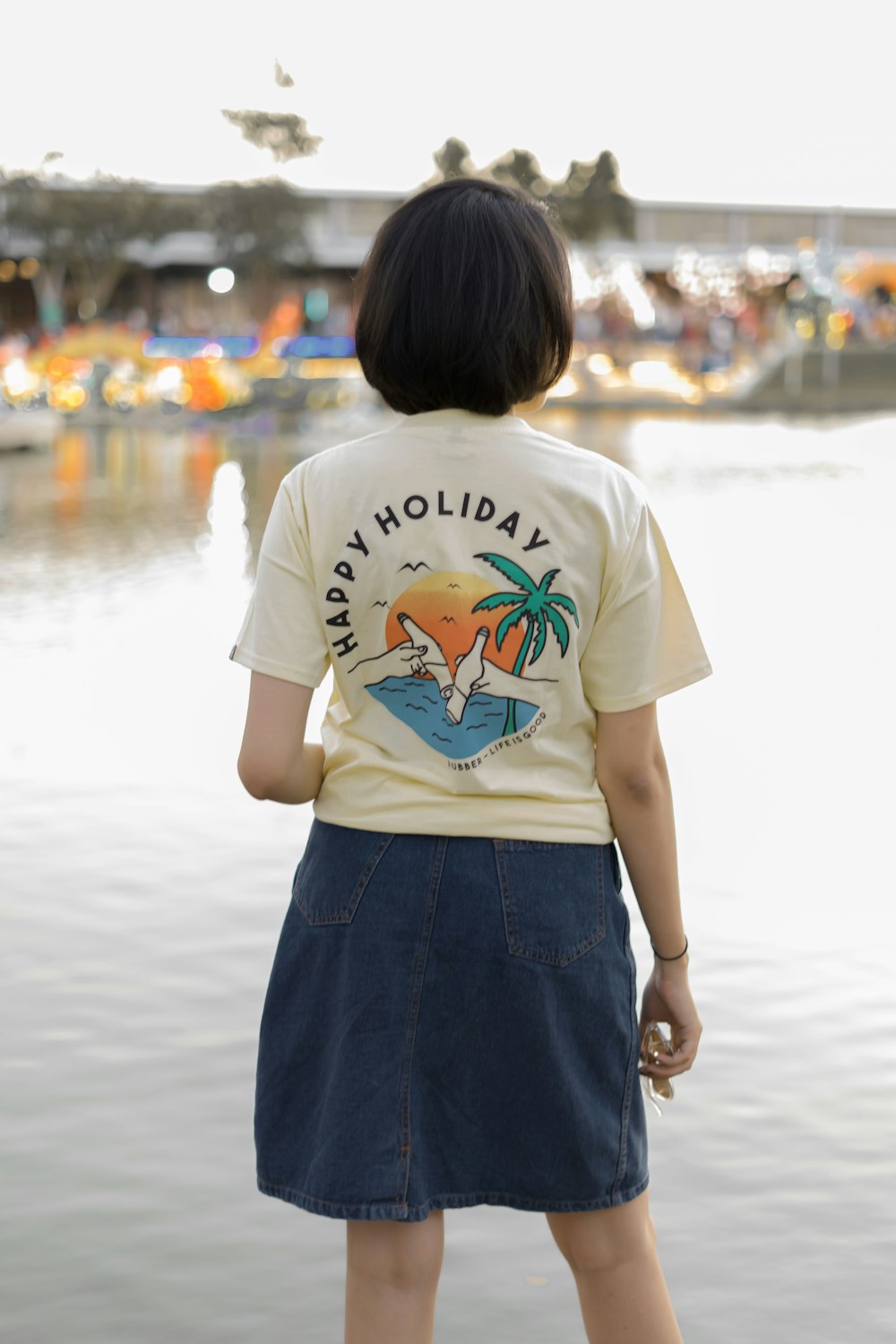 girl in white t-shirt and blue skirt standing on beach during daytime