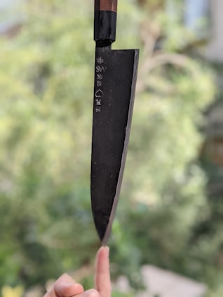A chef instructor demonstrating knife skills to a focused student in a bright, modern kitchen studio.