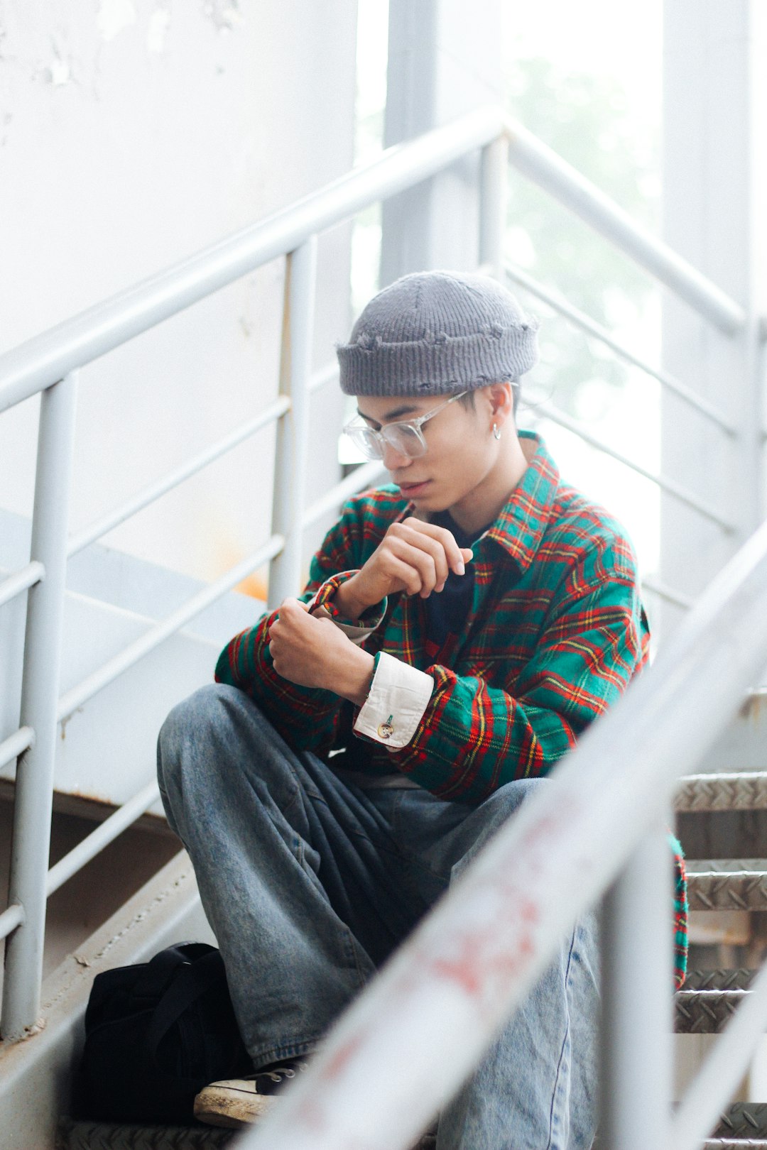 boy in red and blue plaid dress shirt and blue denim jeans sitting on white metal