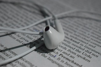 A red 'Goodbye' badge hovering over a tangled pair of budget earbuds on a white background.