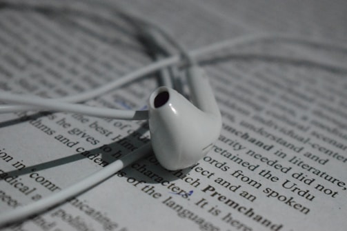 A red 'Goodbye' badge hovering over a tangled pair of budget earbuds on a white background.