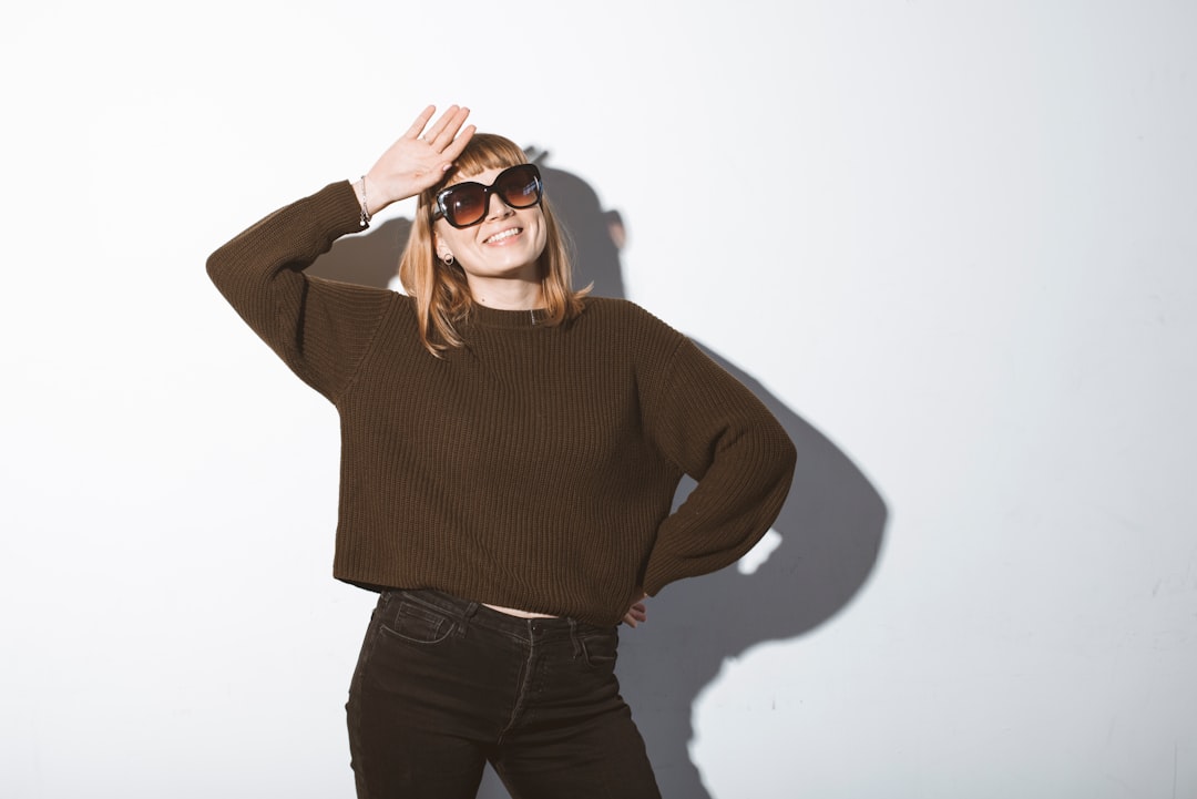 woman in brown sweater and black denim jeans wearing black sunglasses