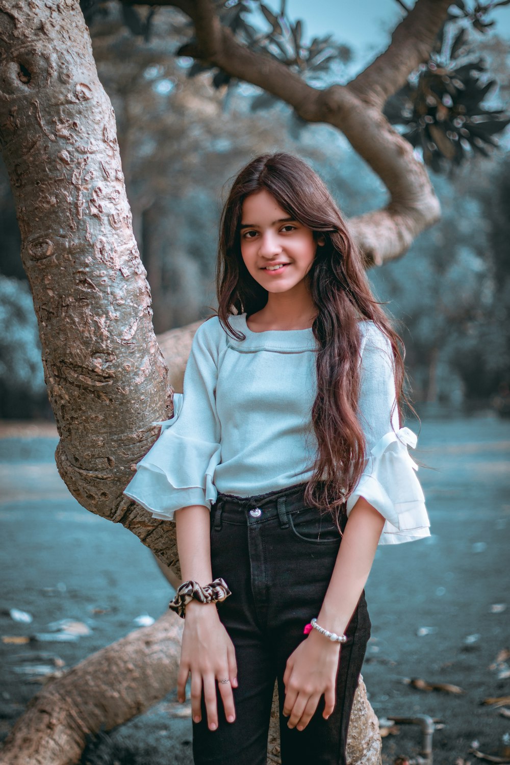 woman in blue denim jacket and blue denim shorts standing beside brown tree trunk during daytime