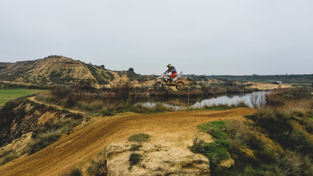 Hombre que monta en motocicleta en el campo de hierba marrón durante el día