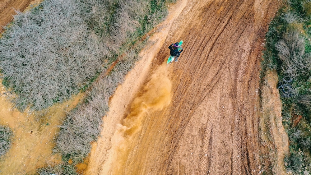 person in blue jacket and blue denim jeans walking on brown dirt road during daytime