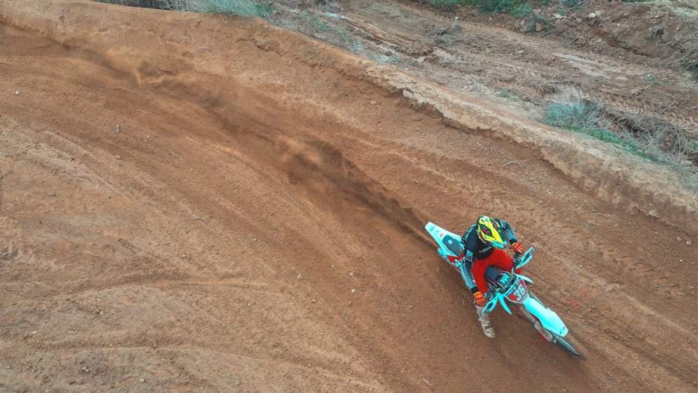 man riding motocross dirt bike on brown sand during daytime