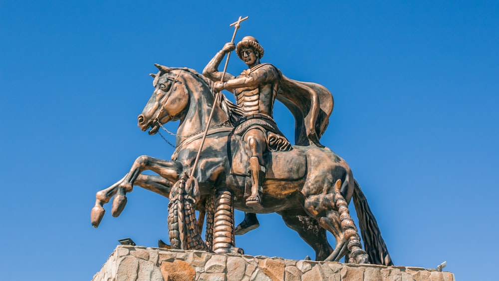 man riding horse statue under blue sky during daytime