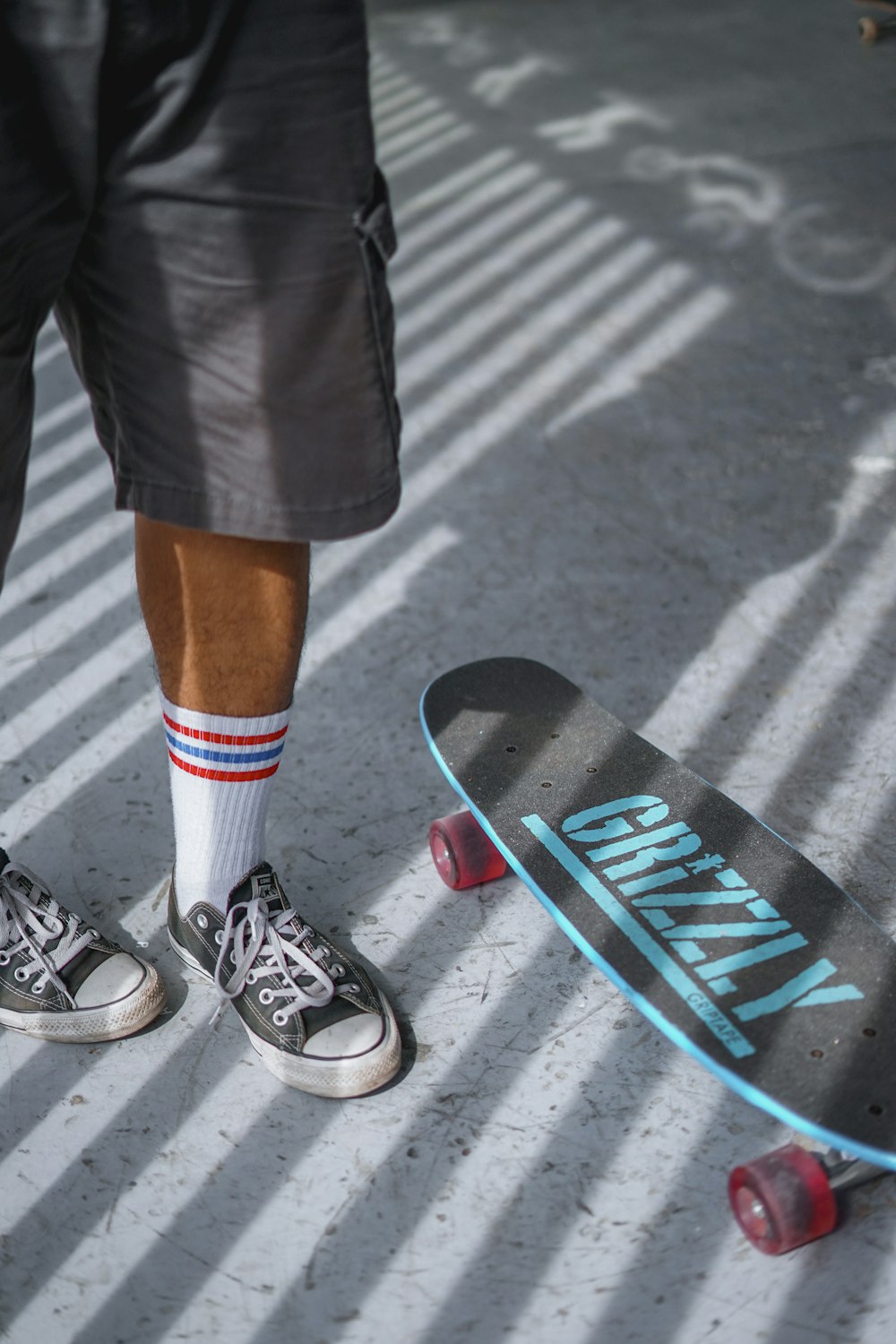 person in black shorts and black and white sneakers standing on gray concrete road during daytime