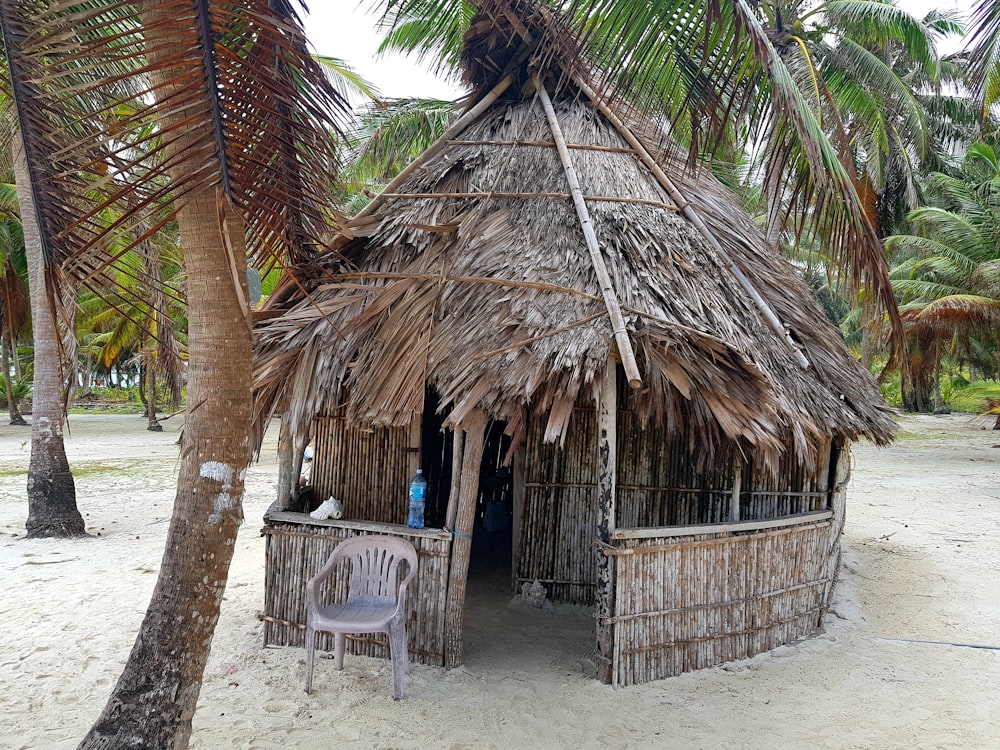 brown wooden nipa hut with white plastic chairs and tables