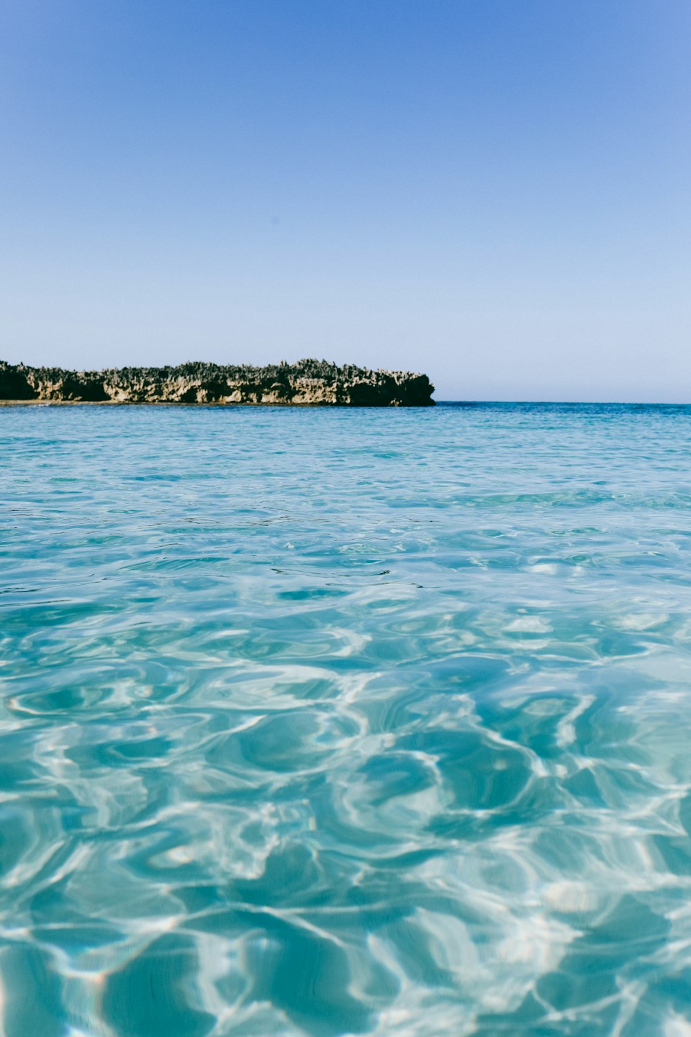 green and brown island on blue sea under blue sky during daytime