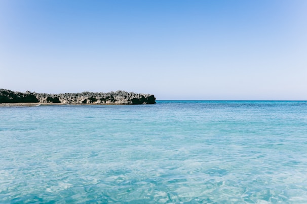A peaceful coastal view of the Mediterranean Sea with clear blue water and a sunny sky.