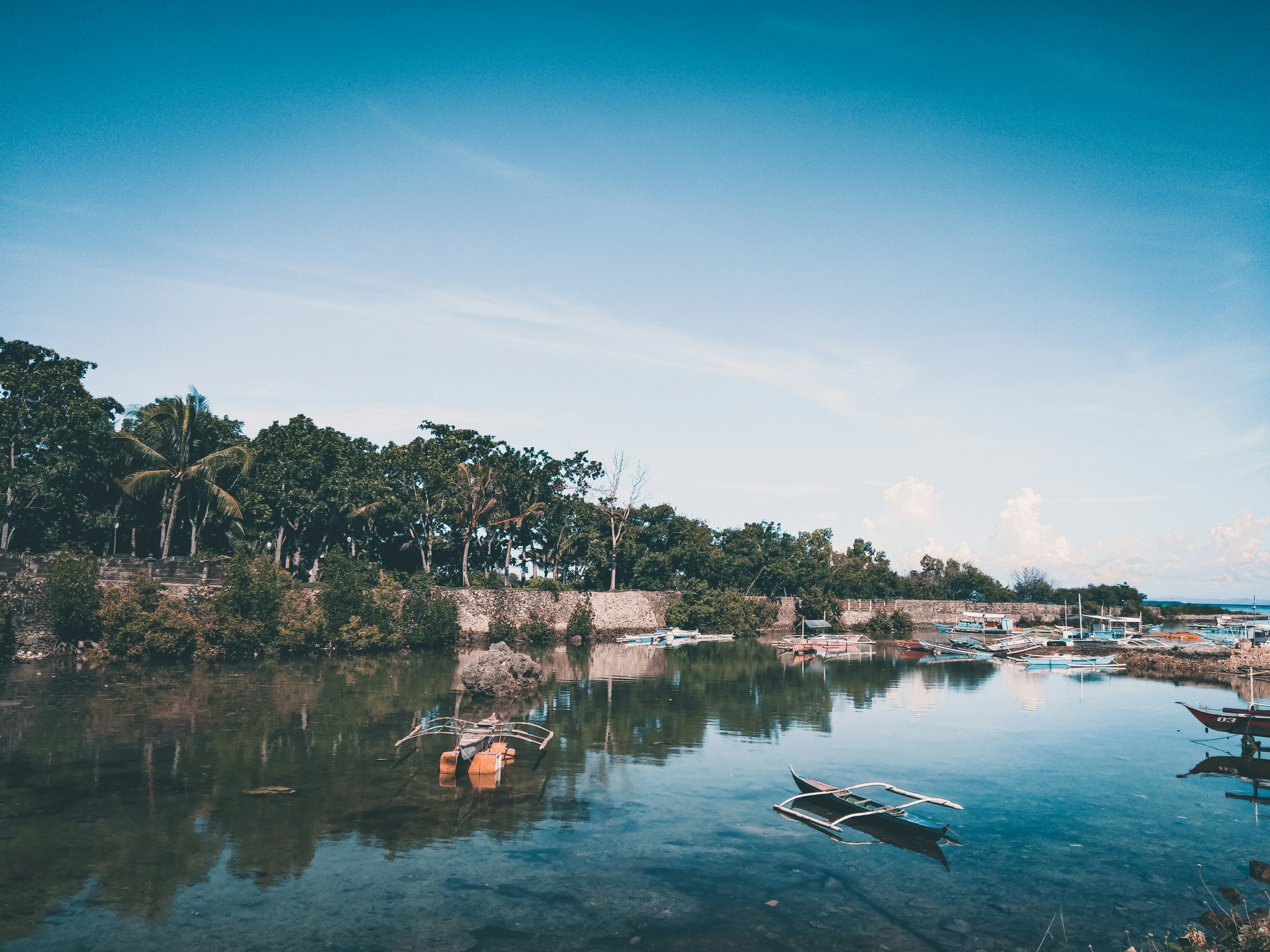 Traditional Kerala wooden country boat on calm backwaters — green coconut palms reflecting in still water