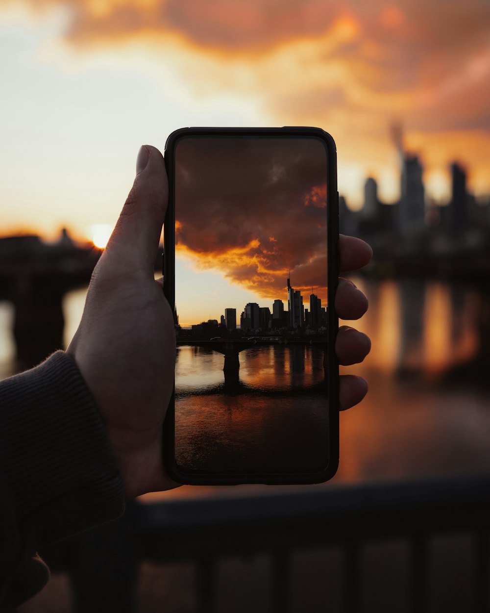 person holding black smartphone taking photo of city buildings during daytime