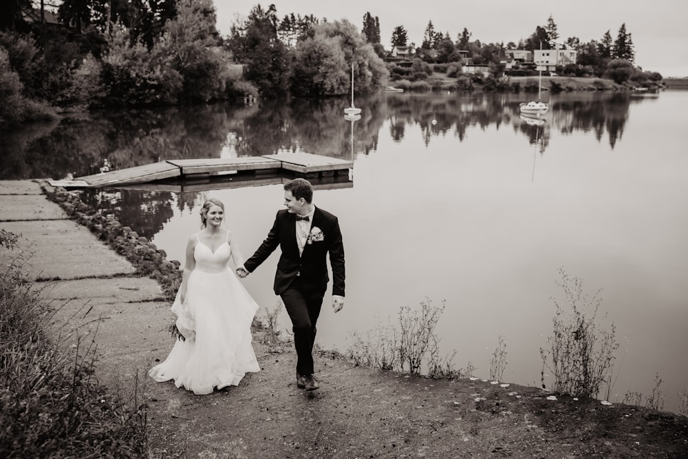 bride and groom standing on brown soil near body of water during daytime