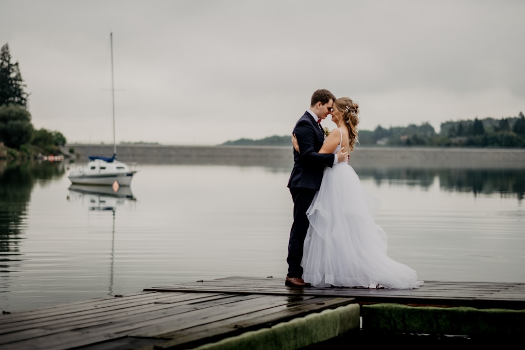 bride and groom standing on wooden dock during daytime