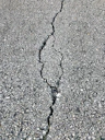Close-up of a cracked and damaged county road surface in Clinton County.