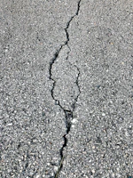 Before and after photos showing a cracked parking lot transformed into a clean, sealed surface.