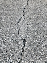 Close-up of workers repairing asphalt on a sunny day.
