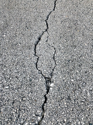 Before and after shots of a cracked, worn pavement transformed into a sleek, durable surface.