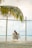 man in white shirt sitting on swing chair under coconut tree during daytime
