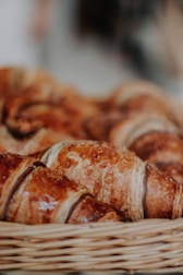 Close-up of golden croissants stacked neatly in a bakery basket.