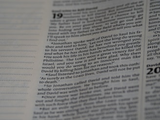 A close-up view of a page from a book, featuring text with a focus on a specific paragraph. The text includes numbers at the beginning of some lines, indicating verses or sections. The page has a slight beige tint, and the text is in a clear, readable font, resembling that of religious or reference material.