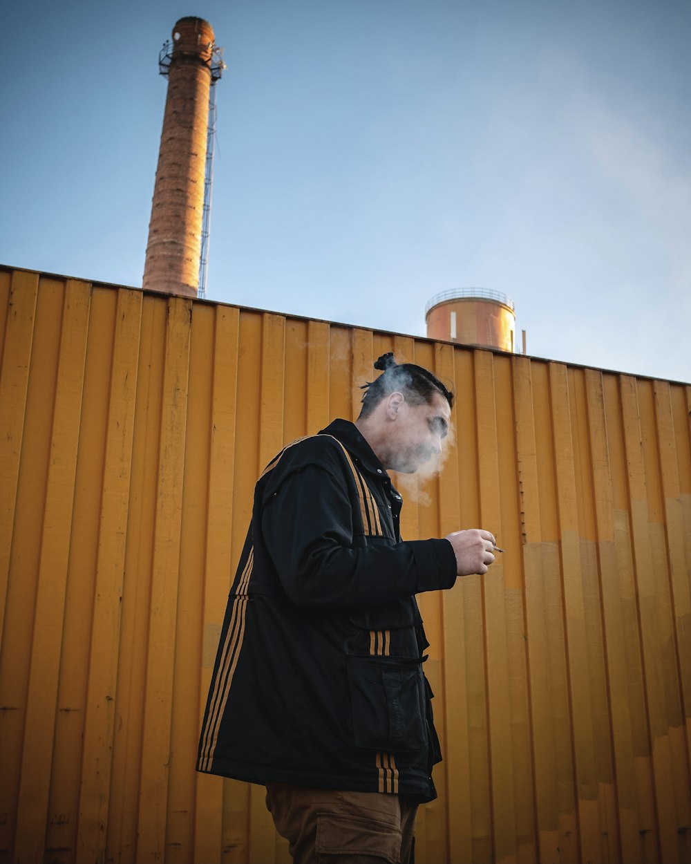 man in black jacket standing near brown wooden wall during daytime